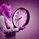 woman holding clock looking anxiously, running out of time