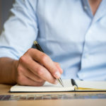 Closeup shot of a man taking down note in a personal organizer.