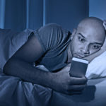 Young Cell Phone Addict Man Awake At Night In Bed Using Smartpho