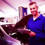 Hood open on a car as a mechanic takes notes